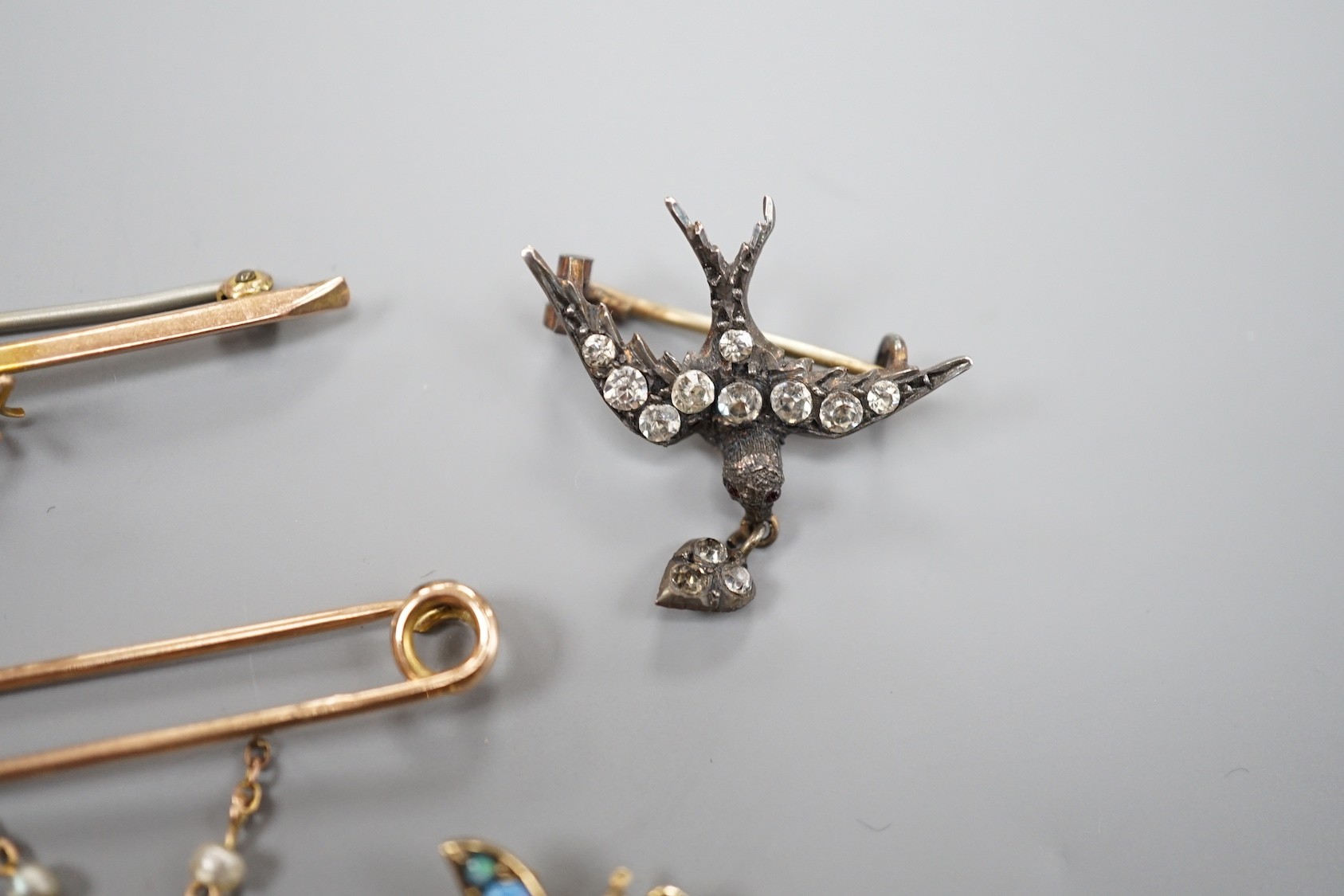 A modern 9ct gold and opal set bug brooch, 24mm, a paste set white metal swallow pendant and similar brooch and two yellow metal bar brooches, one with gem set spider, the other with baroque pearl drop.